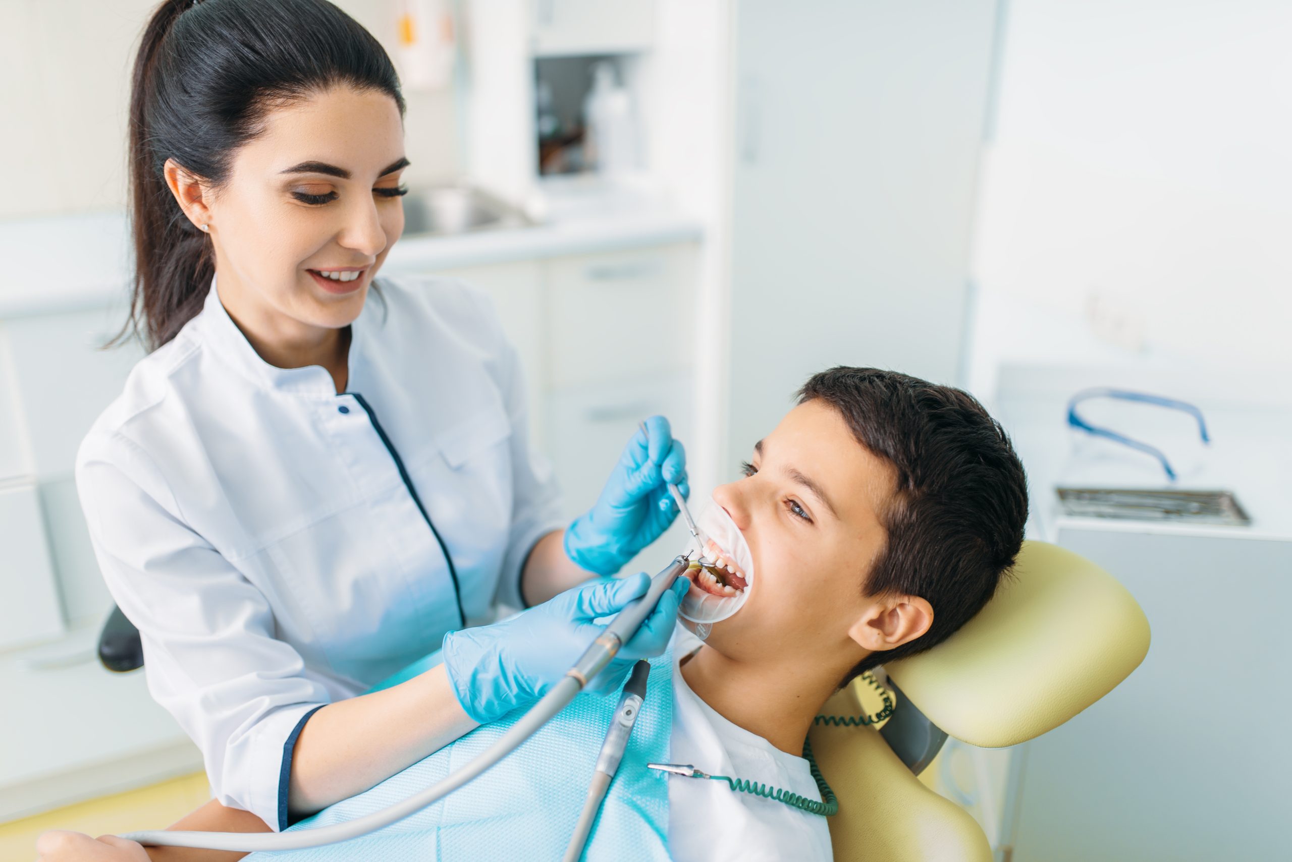 Female dentist gently cleaning a young boy’s teeth during a routine preventive checkup at a modern clinic.